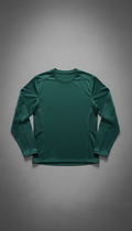 A moisture-wicking athletic top in Teal Green, set against a plain Urban Slate backdrop. The top is centrally positioned,...